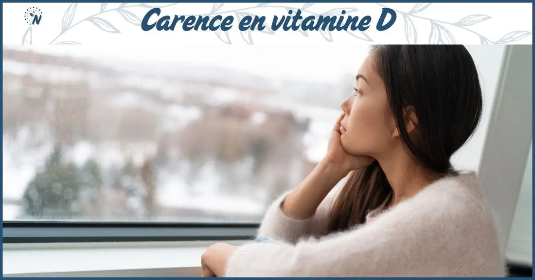 Une femme près d’une fenêtre, dans une lumière hivernale. Bannière blog carence en vitamine D